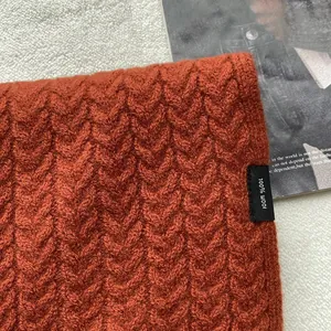 Dettaglio della sciarpa in maglia a trecce 100% lana arancione con trama del tessuto