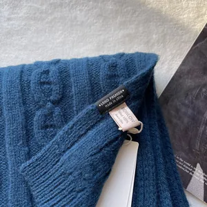 Close-up of a 100% pure wool knitted scarf with brand label and cable knit texture