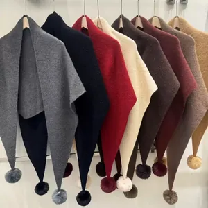 Détail d'écharpes en tricot multicolores avec pompons moelleux sur cintres en bois