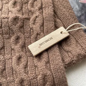 Detail of premium brown cable knit wool texture and natural wooden brand tag