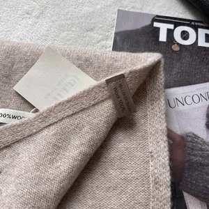 Detailed view of the 100% Australian wool tag on a cream knitted winter scarf