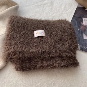 Macro detail of the dark coffee long plush scarf with a colorful BOWLOW woven label
