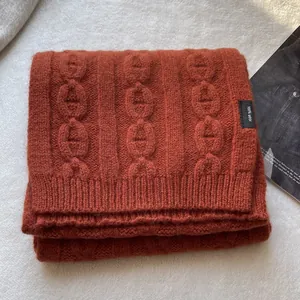 Close-up of orange 100% pure wool knitted scarf with embossed chain pattern texture