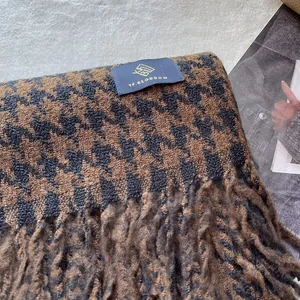 Makroaufnahme von Hahnentritt-Schal mit Markenlabel, Wolltextur und Fransen-Details