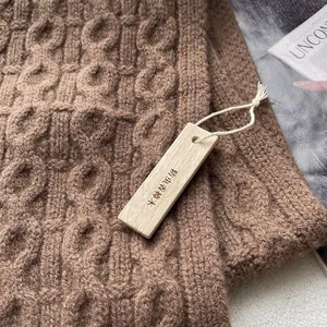 Detail of wool cable knit texture with natural camphor wood anti-moth tag accessory
