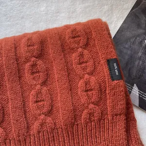 Macro detail of caramel orange 100% wool scarf featuring an embossed anchor chain knit