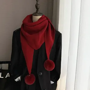 Détail d'une écharpe rouge en tricot avec des pompons doux et texture chaude
