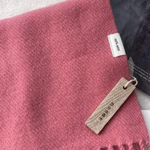 Close-up of pink 100% pure wool scarf with a natural camphor wood anti-moth tag