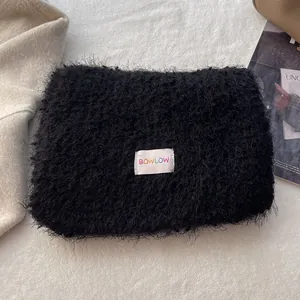 Close-up of black fluffy wool shawl with rainbow BOWLOW label on soft background