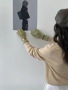 Détail d'un gant en tricot vert avec un poignet côtelé et une petite étiquette logo