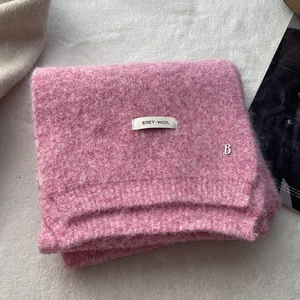 Detail of pink knitted wool scarf with ERET WOOL fabric label and silver metal B charm