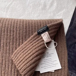 Detailaufnahme des braunen Strickschals aus 100% Wolle mit Markenetiketten und Rippenmuster
