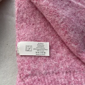 Detail of pink knitted scarf care label showing material blend and soft fuzzy texture