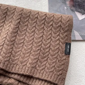 Dettaglio macro della sciarpa in maglia 100% lana marrone scuro con trama a treccia