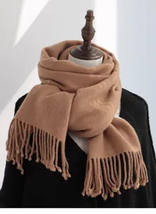 Macro detail of camel wool scarf showing soft woven texture and classic long tassels