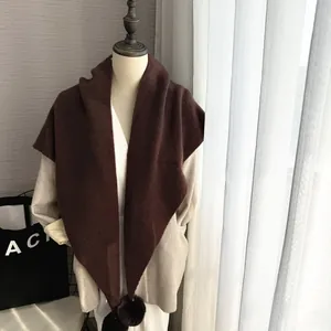 Détail de l'écharpe en tricot marron avec pompons et texture douce en fausse fourrure