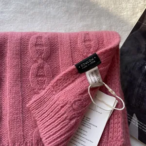 Detail showing pink 100% wool cable knit texture and official brand labels