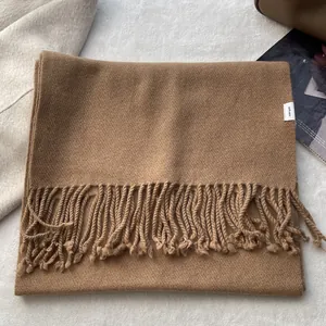 Detail of camel wool scarf with fringe and 100% WOOL label on soft woven fabric