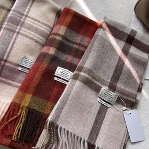 Detailweergave van 100% wollen geruite sjaals met franjes in beige, oranje en grijs