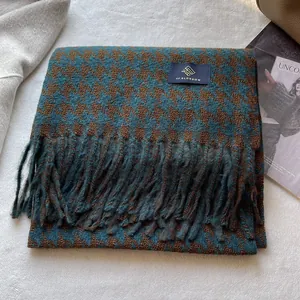 Detail eines blauen Hahnentritt-Schals mit dicken Quasten und Premium-Markenlabel
