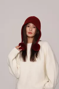 Dettaglio del passamontagna in lana bordeaux con grandi pompon e calda trama a maglia
