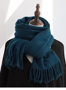 Close-up of thick teal pure wool scarf with soft fringe tassels on a display model