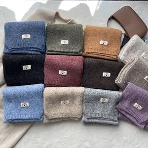 Flat lay of wool blend knitted scarves in 12 colors with melange effect and woven labels