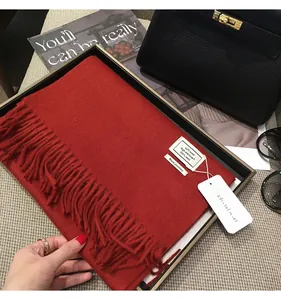 Dettaglio sciarpa in pura lana rossa con frange e confezione regalo di lusso nera