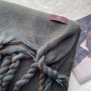 Vue détaillée d'une écharpe à carreaux bleu et marron avec pompons et étiquette tissée