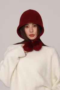 Dettaglio del passamontagna in lana bordeaux con texture morbida e pompon di peluche