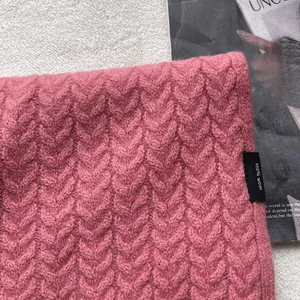 Dettaglio di sciarpa in lana rosa 100% con classica trama a trecce vintage ed etichetta