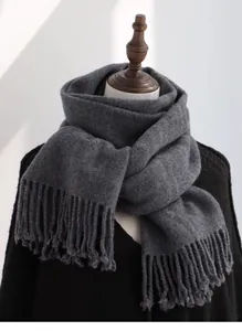 Detailed view of thick grey wool scarf texture with soft tassels on black knitwear