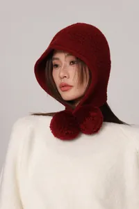 Dettaglio passamontagna in lana rosso scuro con grandi pompon decorativi abbinati