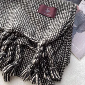 Détail de l'écharpe à carreaux noir et blanc avec de larges franges et étiquette tissée