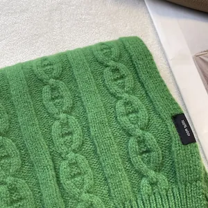 Macro detail of grass green 100% wool knit scarf featuring premium chain pattern texture
