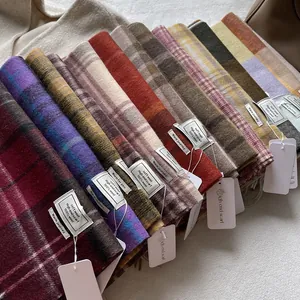 Blue plaid and colorful 100% wool scarves stacked to show soft textures and labels