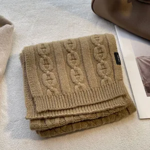 Macro detail of camel 100% pure wool scarf with thick chain knit texture and brand label