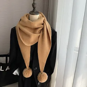 Détail de l'écharpe en tricot camel avec deux pompons en fausse fourrure de lapin doux
