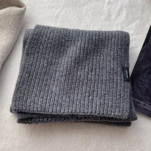 Detail eines Schals aus 100% Wolle mit grauer Rippenstruktur und Materialetikett