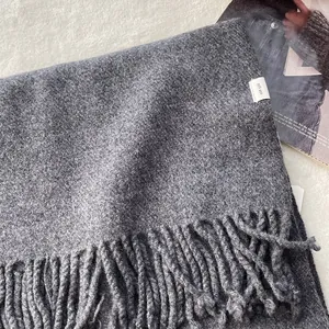 Macro detail of dark grey 100% pure wool scarf texture with twisted tassel fringe edge
