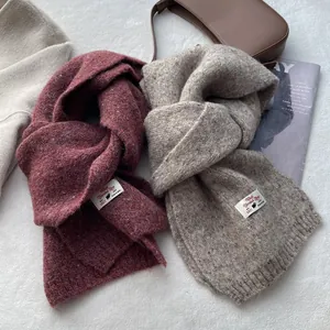 Detailed close-up of wool blended knitted scarves in burgundy and oatmeal colors