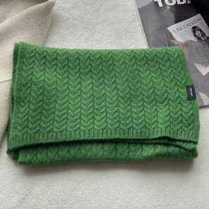 Dettaglio della trama della sciarpa in lana verde lavorata su uno sfondo elegante