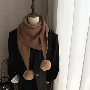 Détail d'une écharpe en maille douce avec pompons en peluche sur un mannequin chic