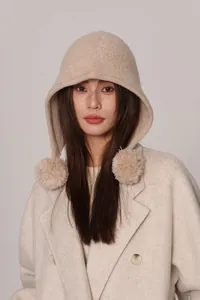 Dettaglio del passamontagna in lana con pompon di pelliccia beige su maglia pregiata