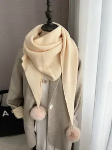 Détails de la maille d'une écharpe crème avec pompons amovibles en fausse fourrure