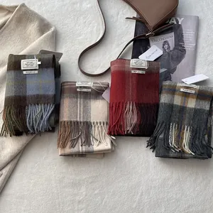 Close-up of four plaid 100% wool scarves with tassels and premium stitched labels