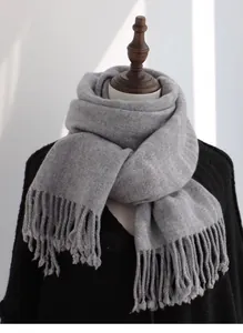 Detail of light gray pure wool scarf with thick fringe on a display mannequin