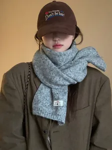 Detailed texture of thick grey wool blend knit scarf with embroidered baseball cap