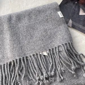 Detail of grey 100% pure wool scarf featuring soft fringe and authentic fabric care label