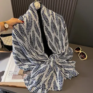 Ethnic cotton-linen scarf with navy blue leaf patterns draped on a fashion mannequin